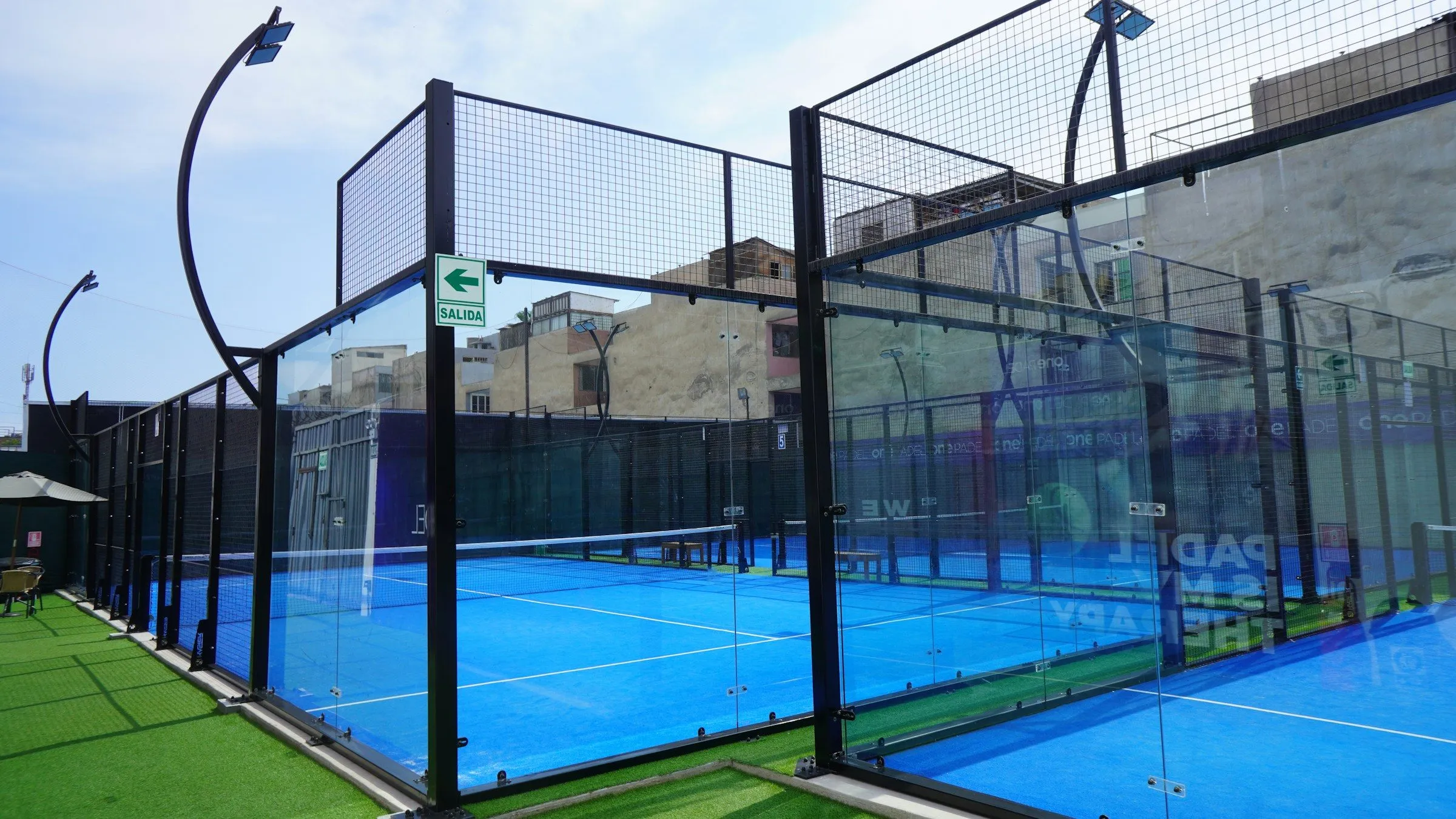 Outdoor-Padelcourt mit Glaswänden an der Stirnseite und Gitter an den Seiten