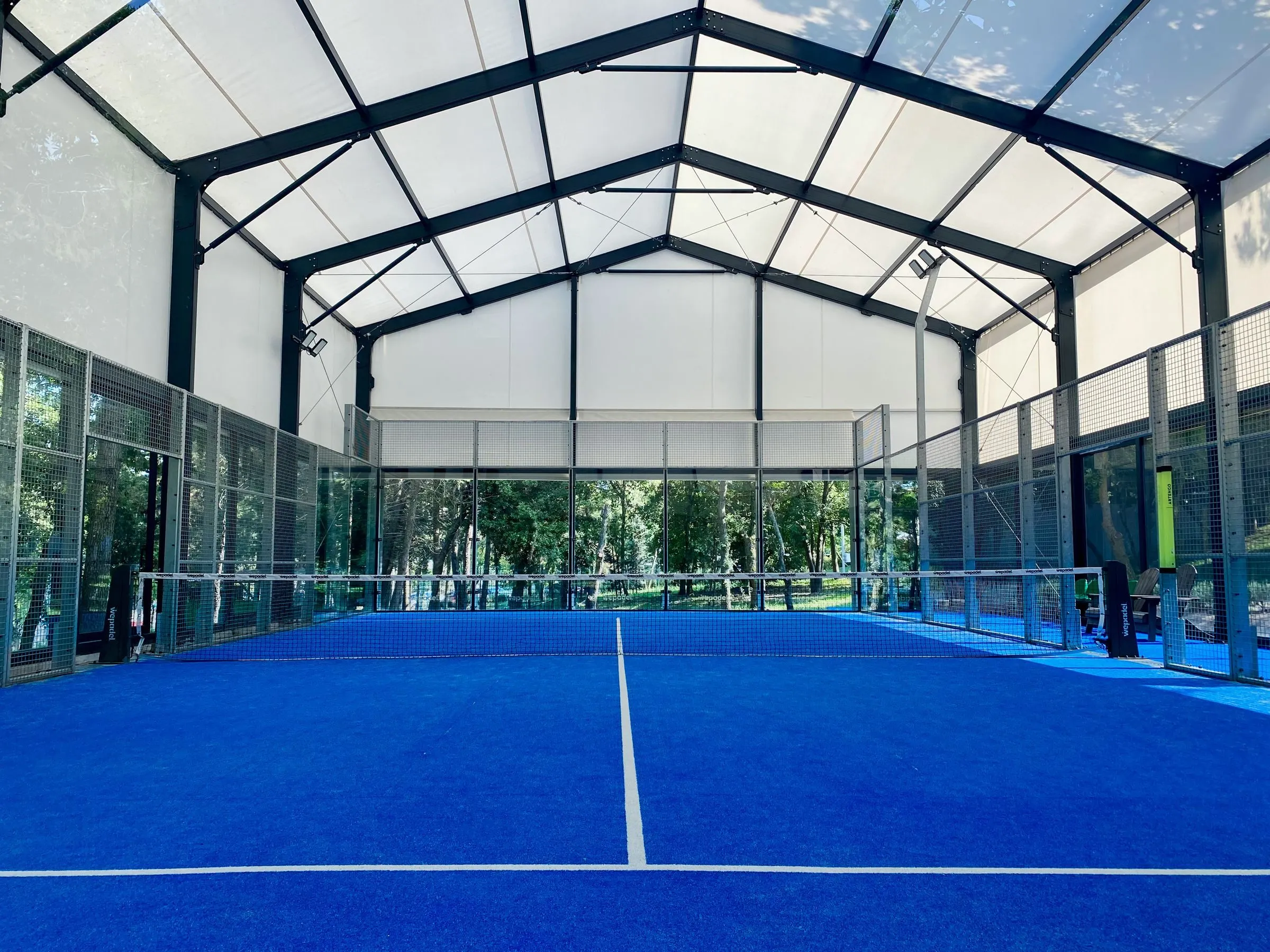 Moderne Indoor-Padelhalle mit mehreren blauen Courts unter einem hohen Dach
